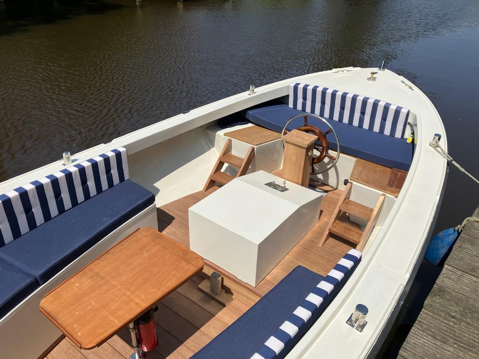 Sloep met blauw-wit gestreepte kussens en teakhouten tafel