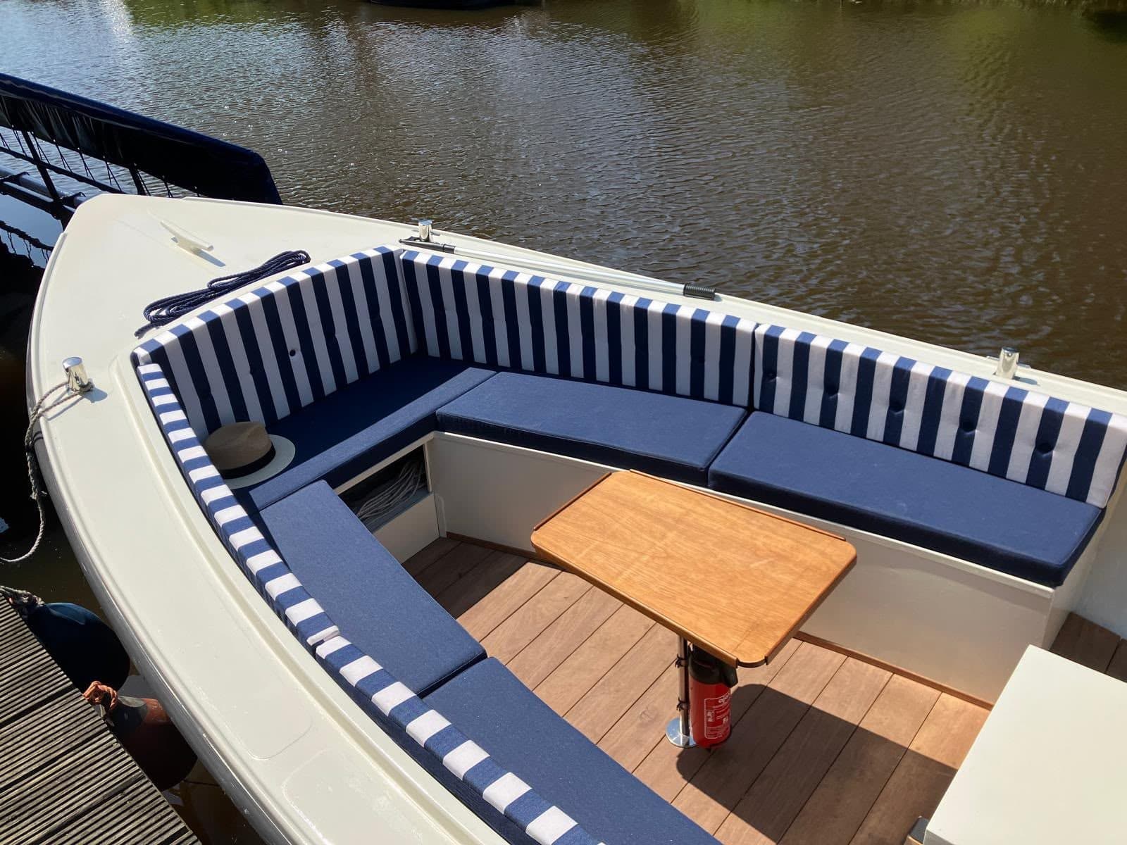 Open sloep met blauwe zitkussens en blauw-wit gestreepte rugkussens